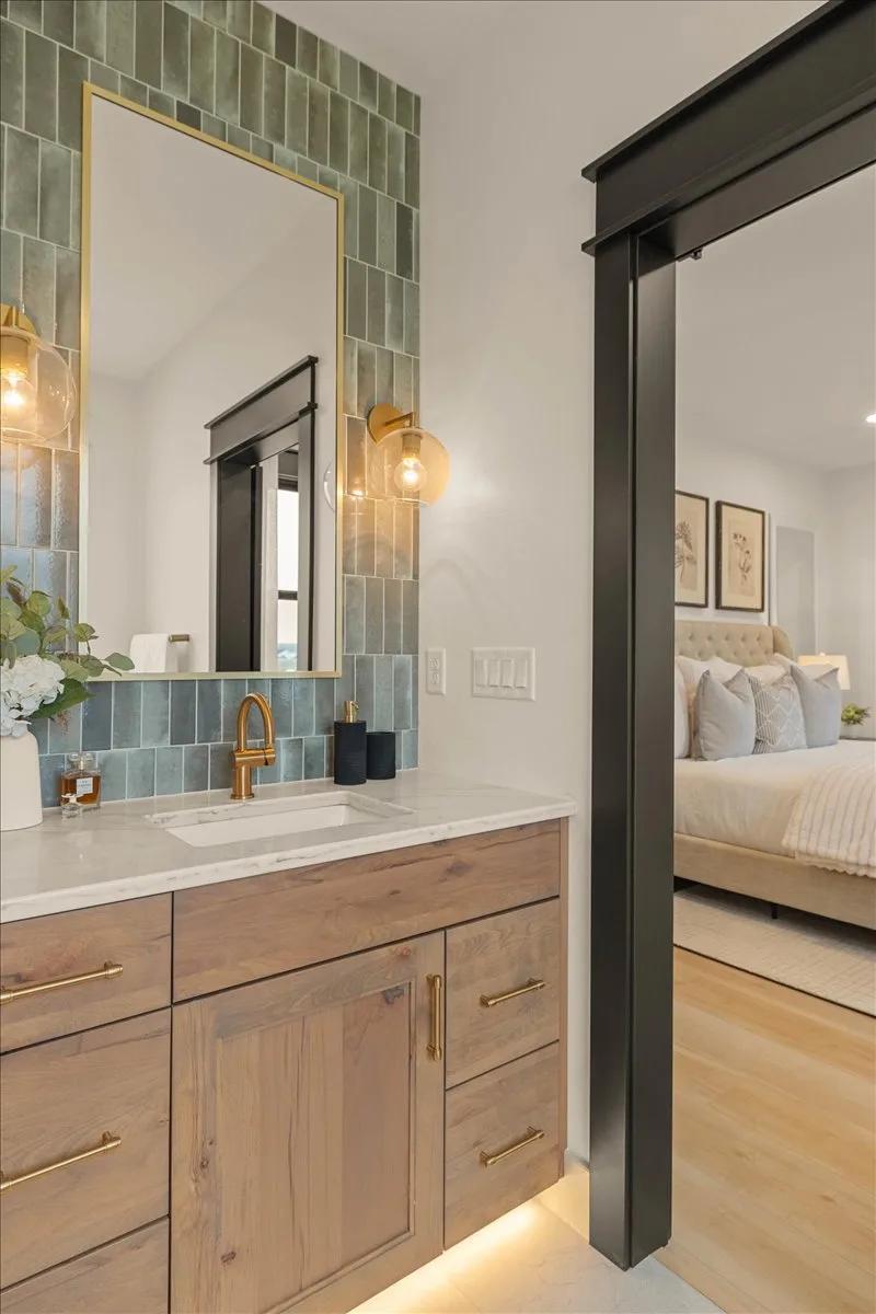 Bathroom vanity in Rustic Beech with an Almond stain, gold hardware, and a green stacked tile backsplash