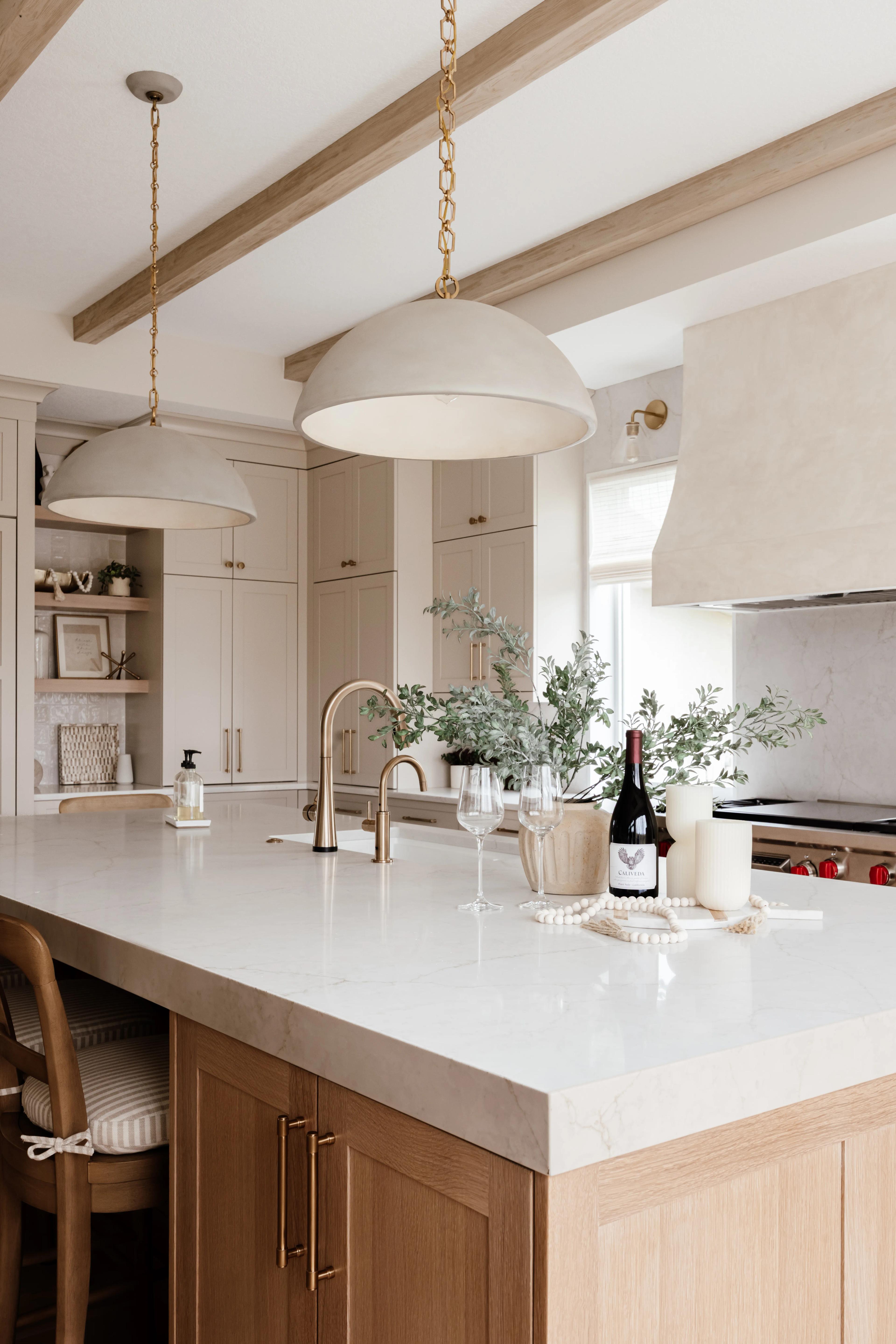White Oak Plateau island in Sand stain with a pale stone countertop, gold faucet, and Accessible Beige cabinets beyond