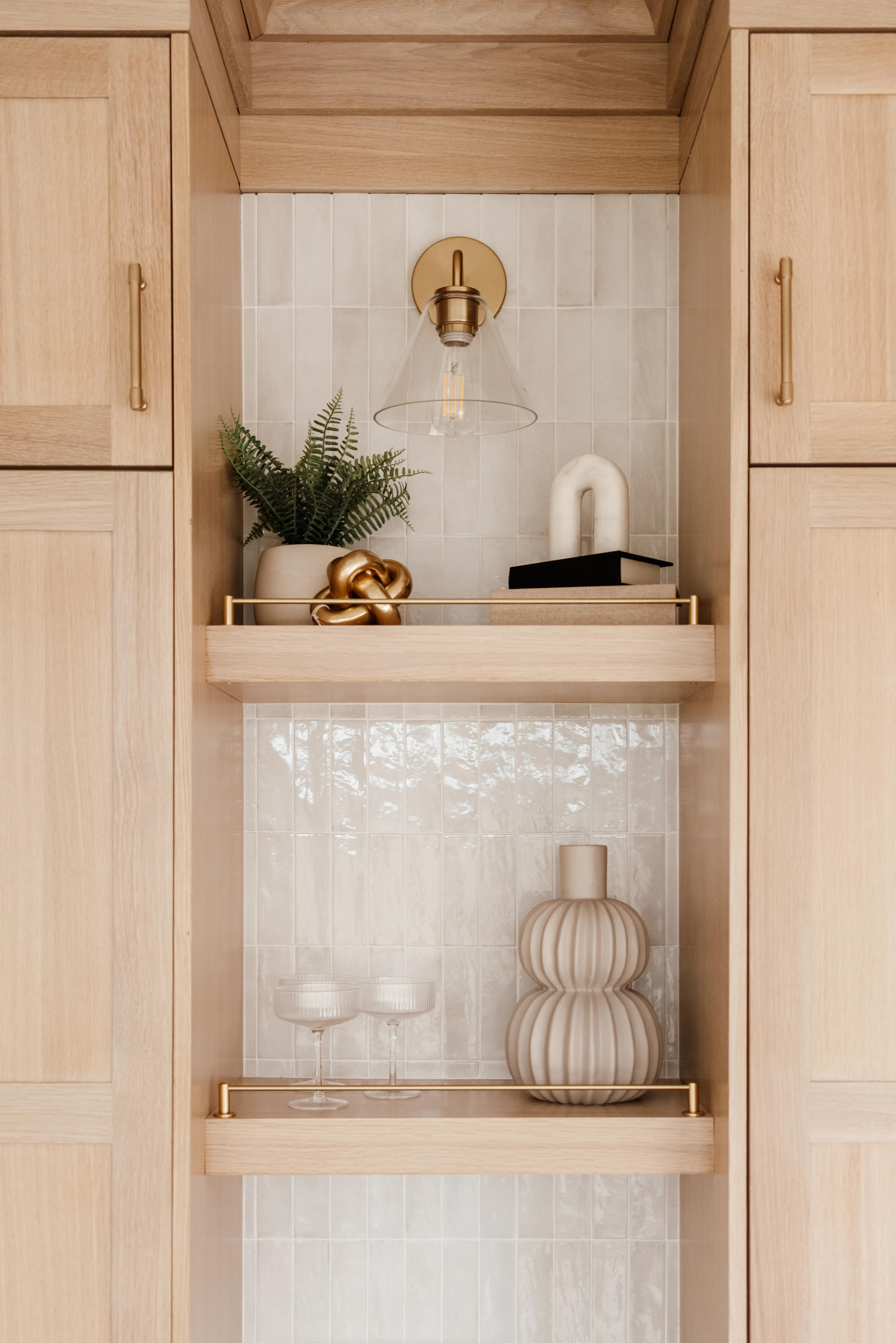 Close-up of White Oak shelves in Sand stain with a gold rail and tiled dry-bar niche